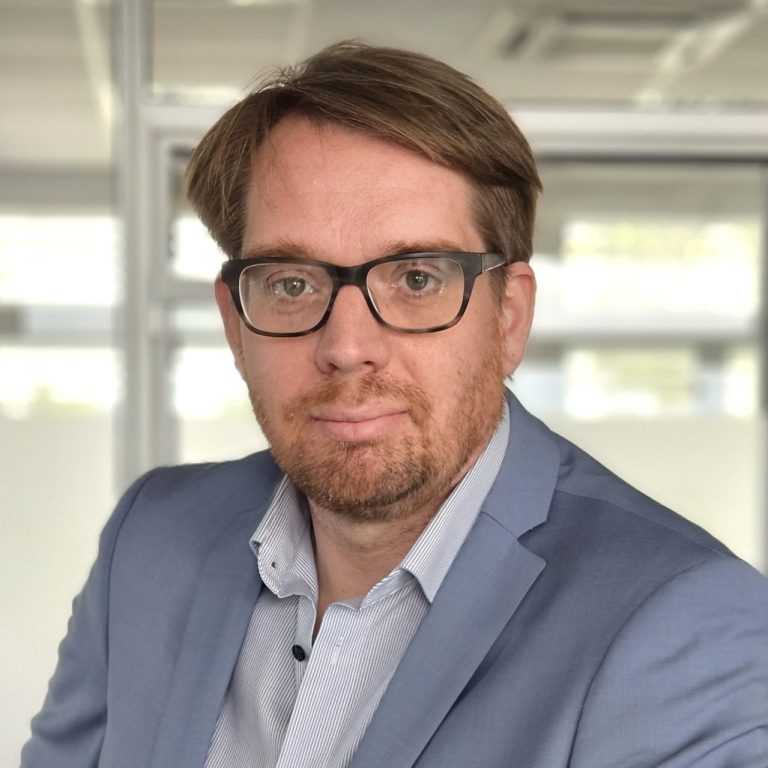 RA Thorsten Wurz Mann mit Brille und blauem Anzug, neutraler Gesichtsausdruck, moderner Büro-Hintergrund.