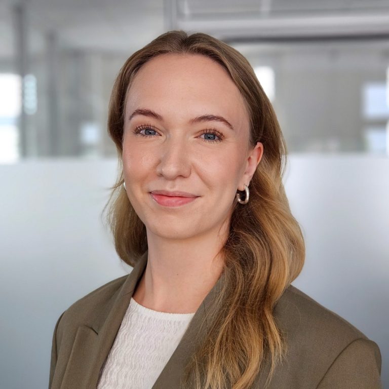 RAin Svenja Seifried Junge Frau mit blonden Haaren in einem Büro, trägt einen eleganten Blazer.